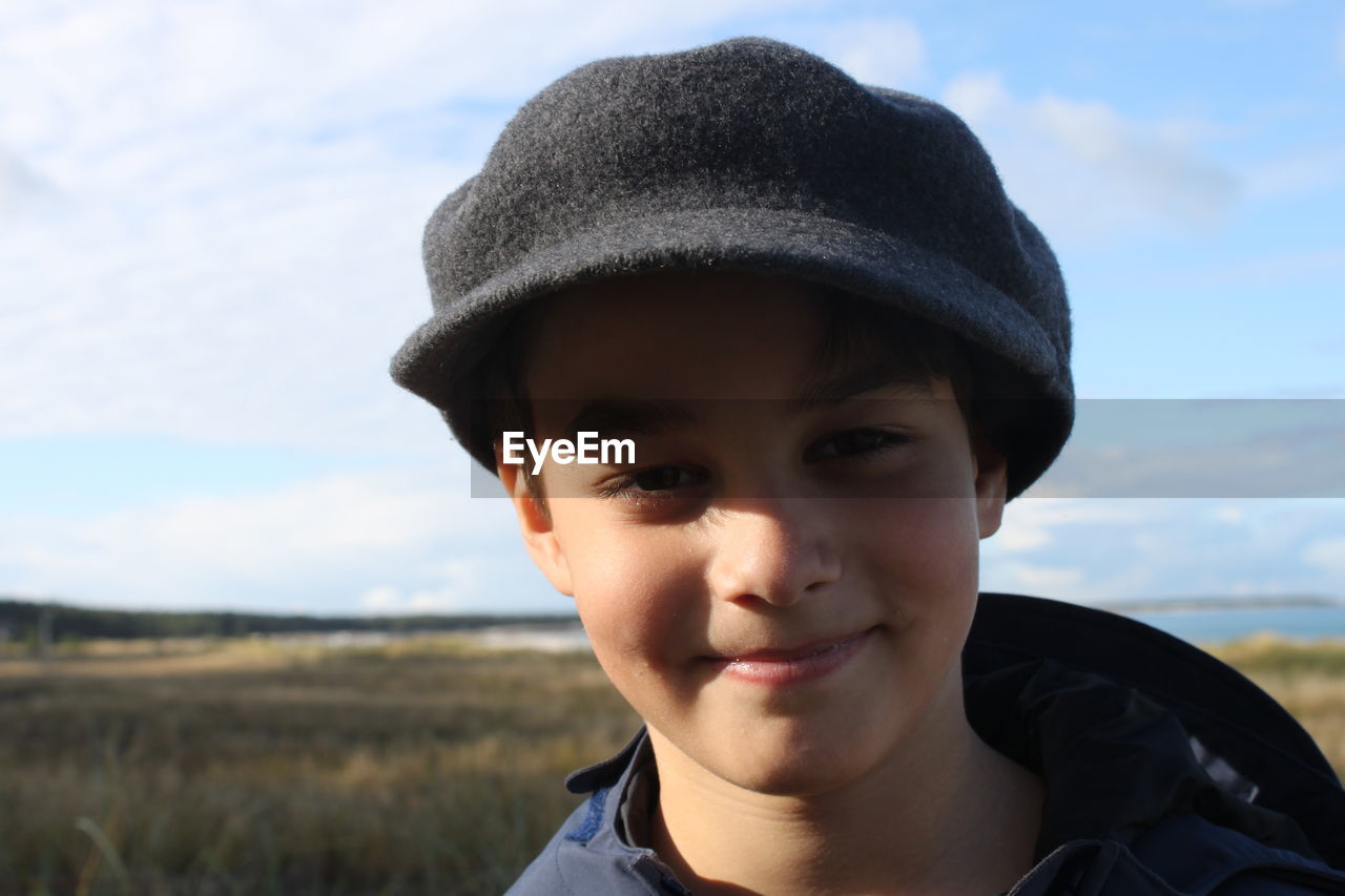 Portrait of teenage boy wearing cap against sky