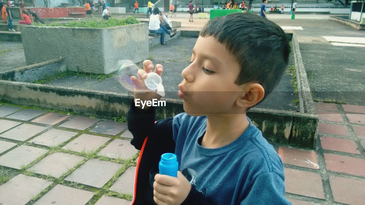 Cute boy blowing bubble at park