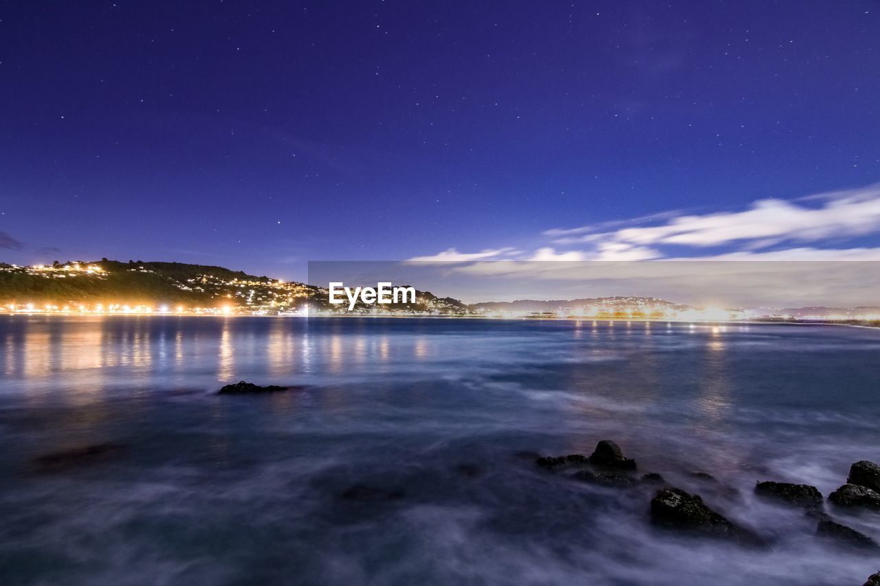 ILLUMINATED SEA AGAINST SKY AT NIGHT