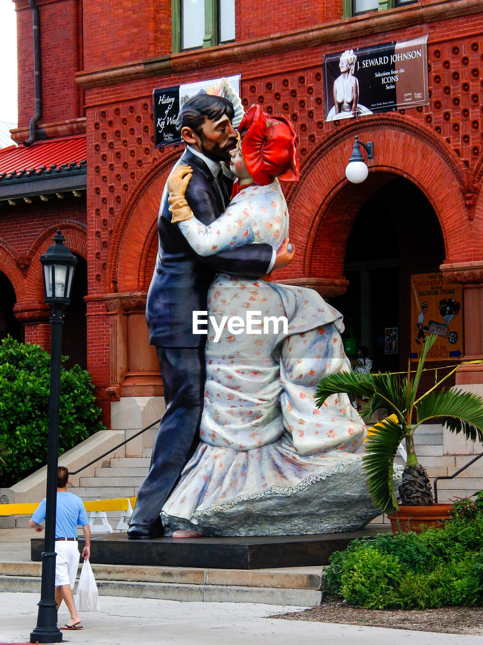 STATUE OF MAN AND WOMAN WALKING OUTSIDE BUILDING