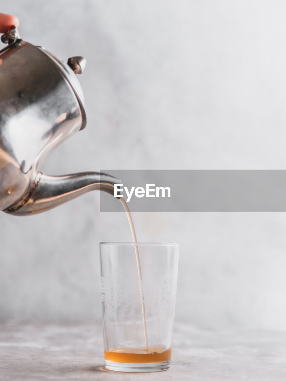 Close-up of moroccan mint tea being poured in glass on grey table