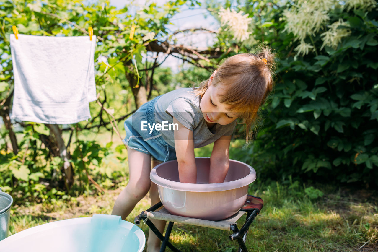 Little preschool girl helps with laundry. child washes clothes in garden