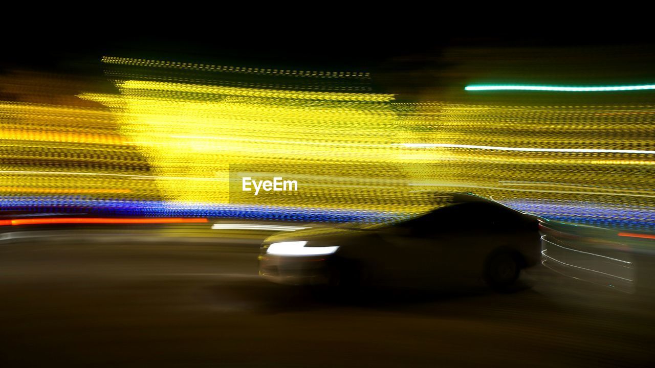Blurred motion of car with light trails on road