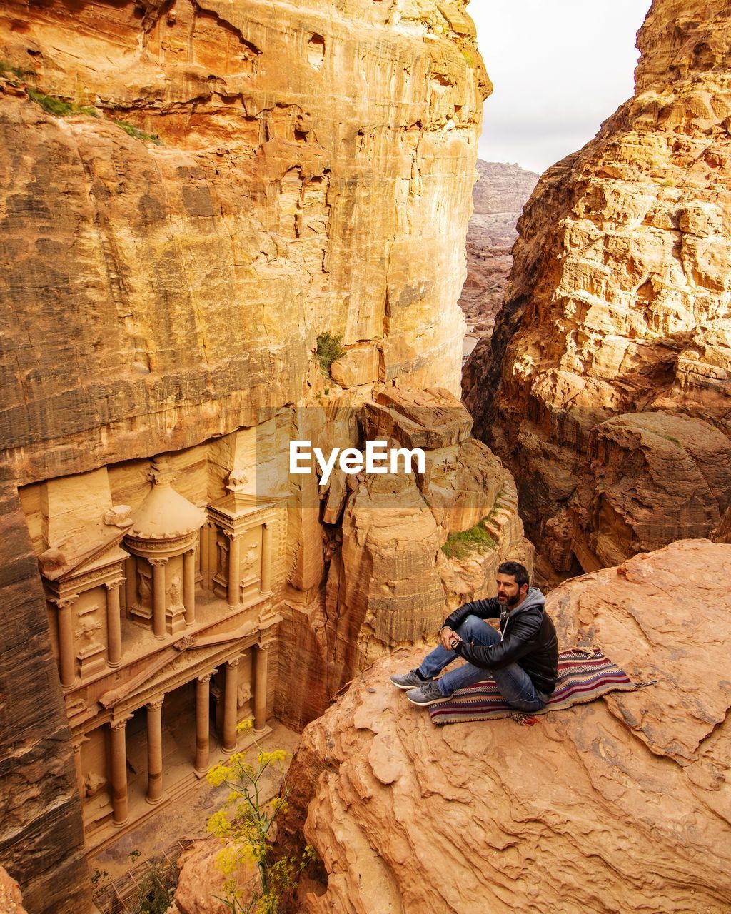 Man sitting on rock formation by historic building