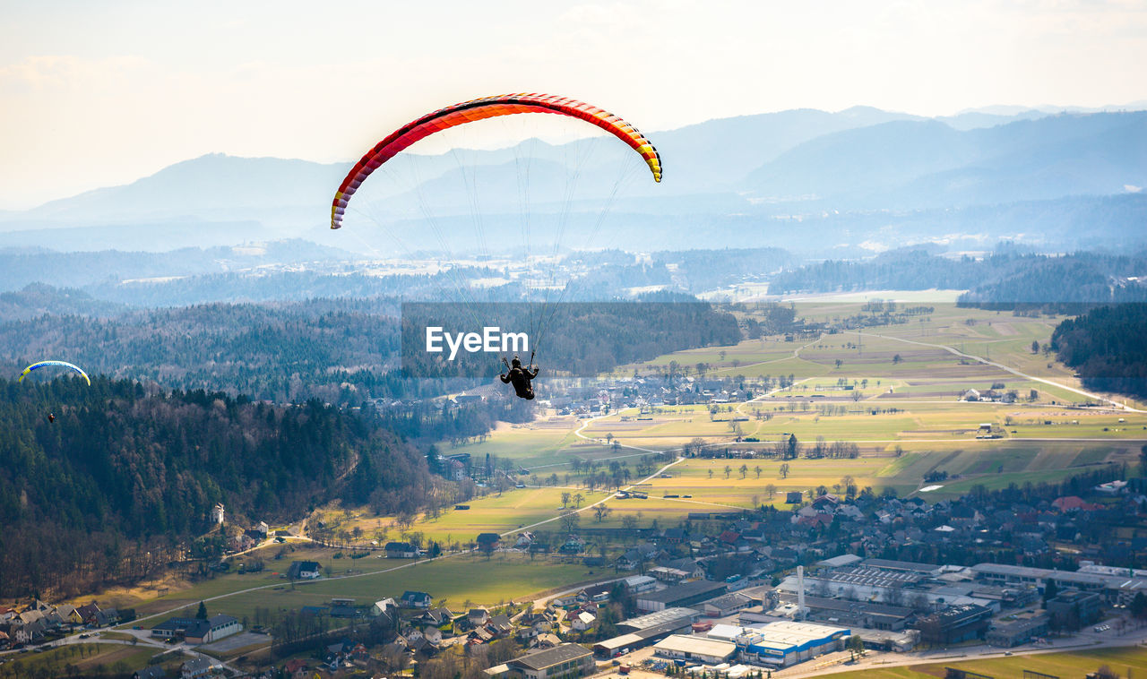 Person paragliding over village