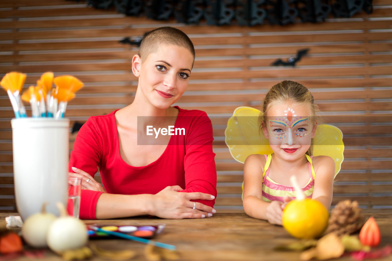 Portrait of smiling mother and daughter sitting at home