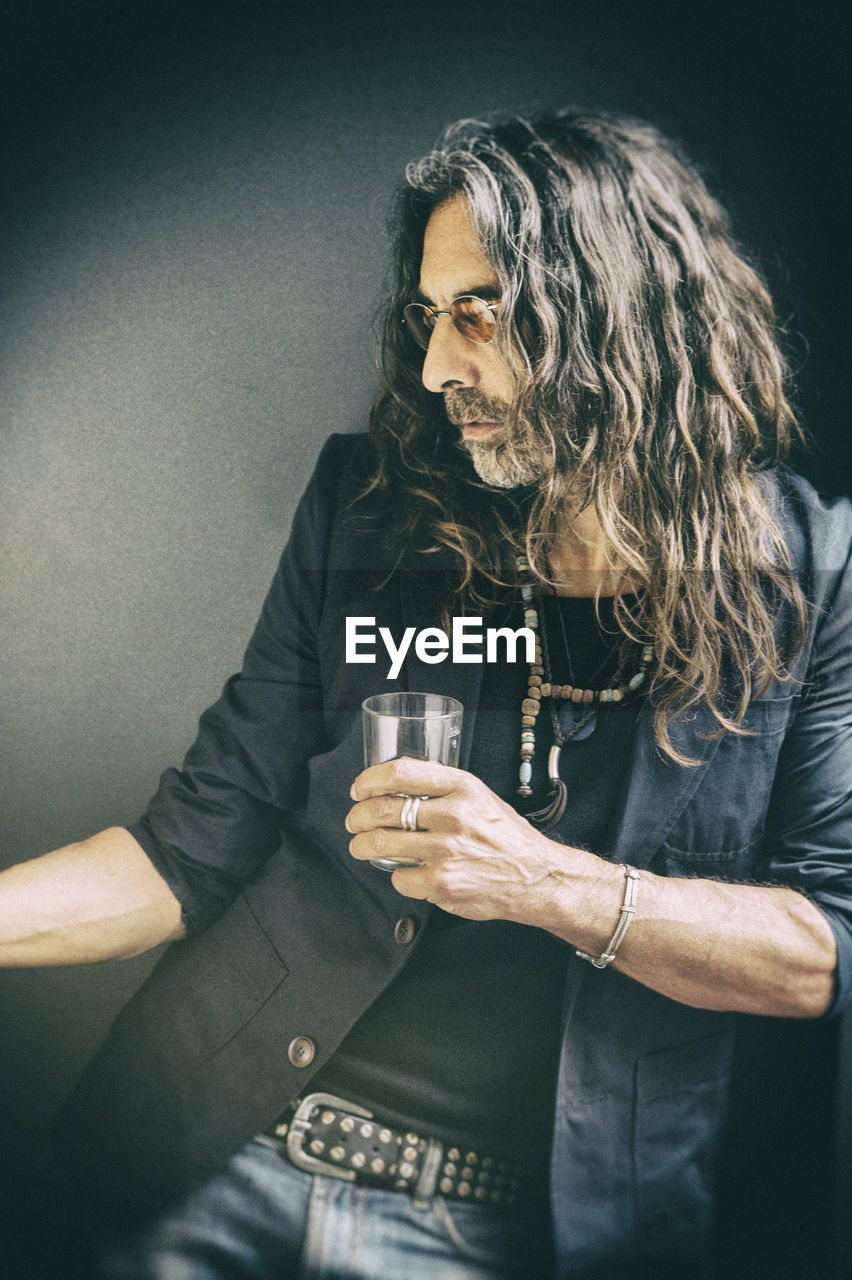 Man holding drinking glass on black background