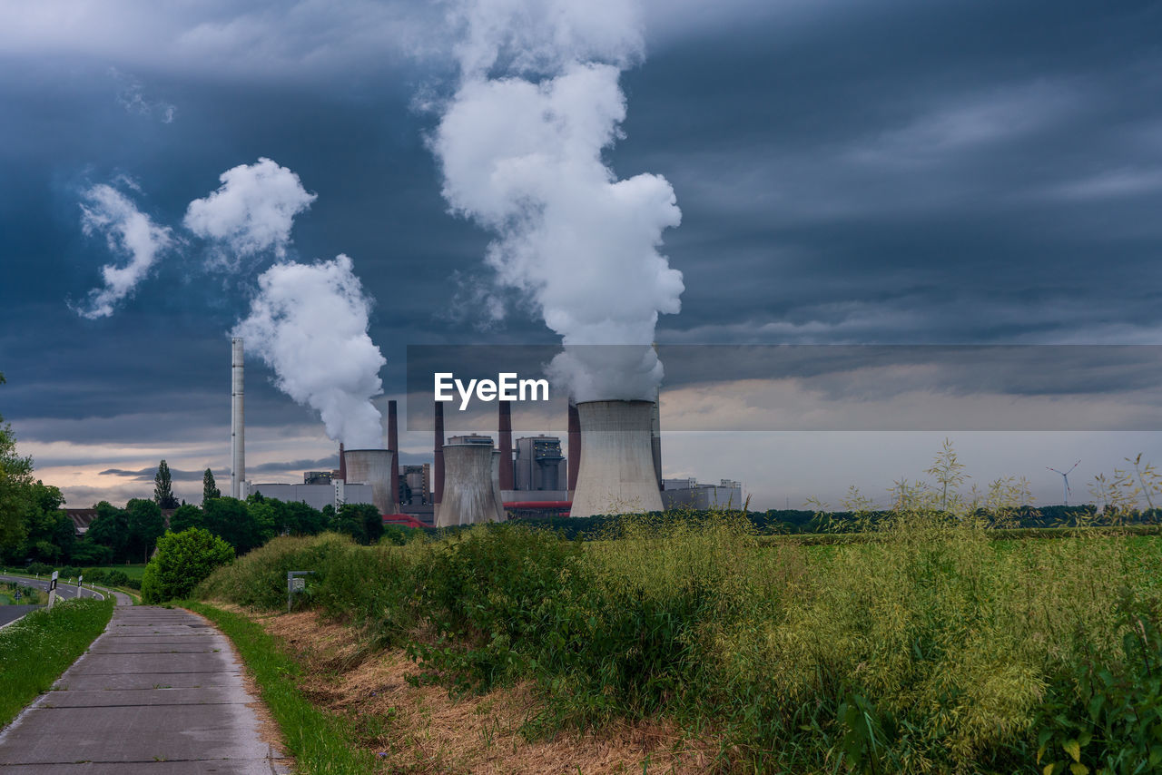 Smoke emitting from factory against sky