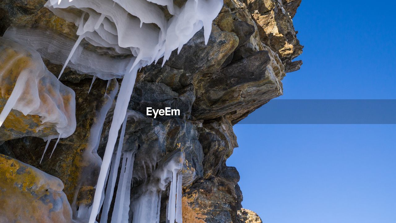 LOW ANGLE VIEW OF ROCK FORMATIONS AGAINST BLUE SKY