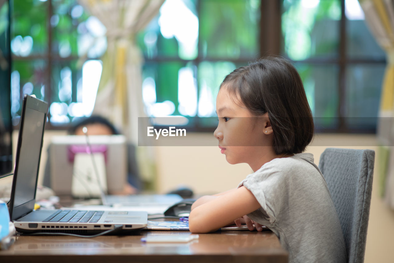 Asian child doing online learning or e-learning at home