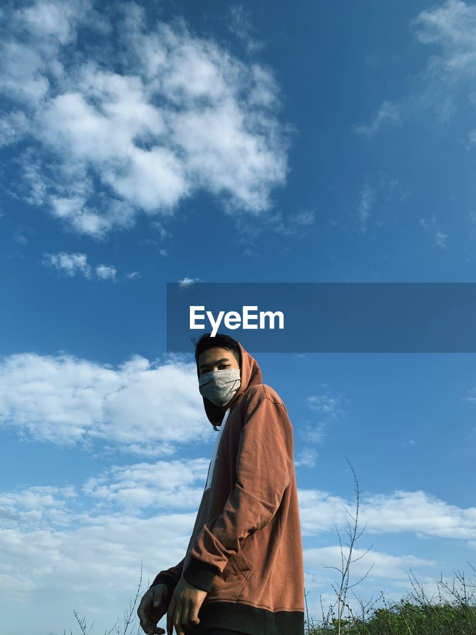 Low angle view of man wearing mask against sky