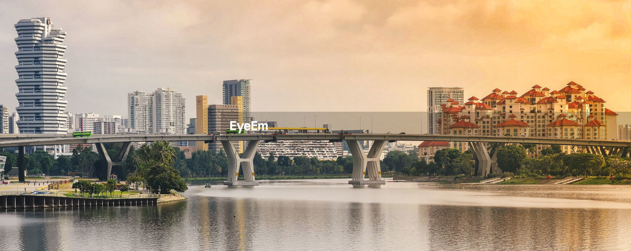 Bridge over river by buildings against sky in city