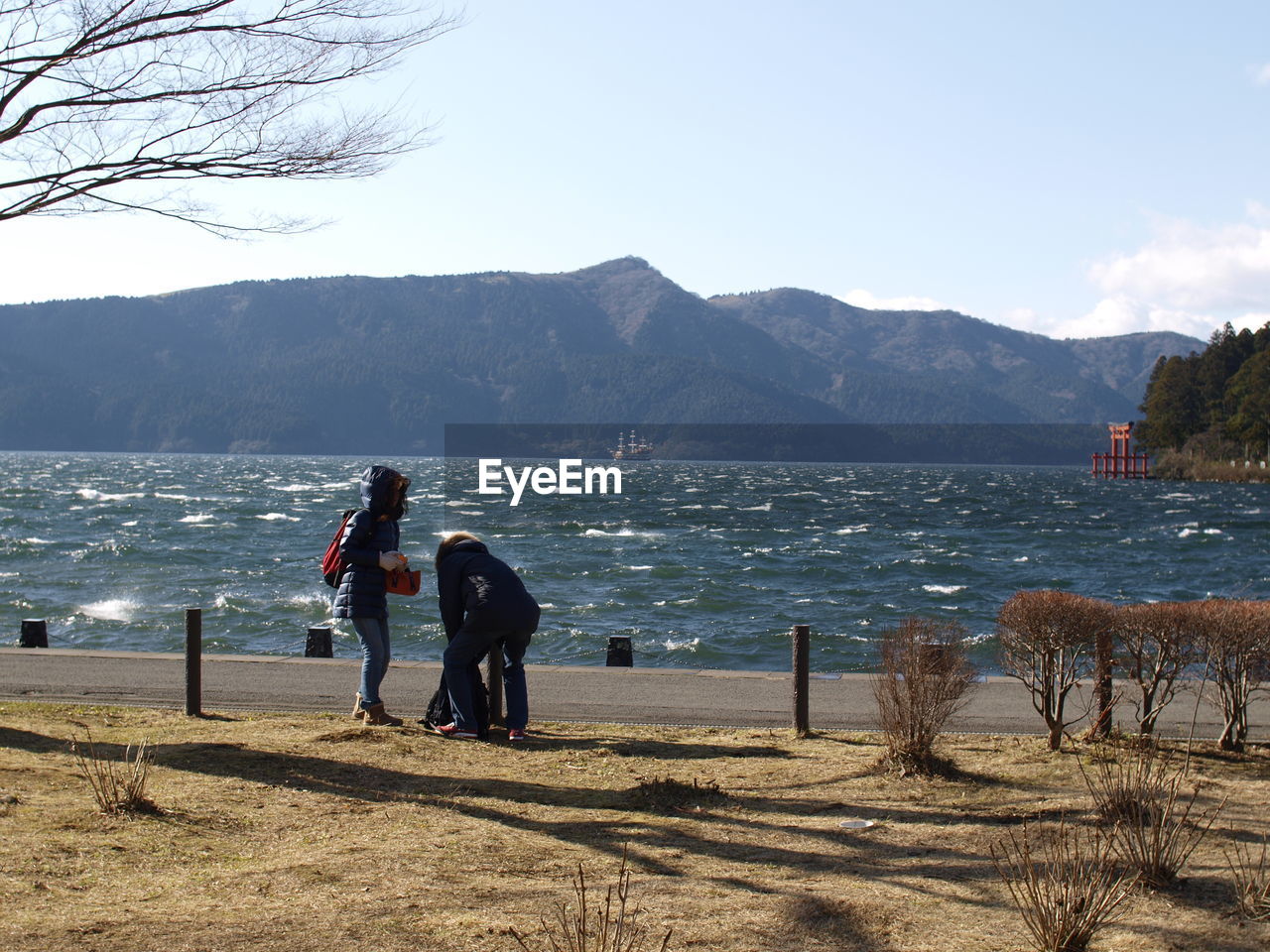 PEOPLE ON BEACH AGAINST MOUNTAINS