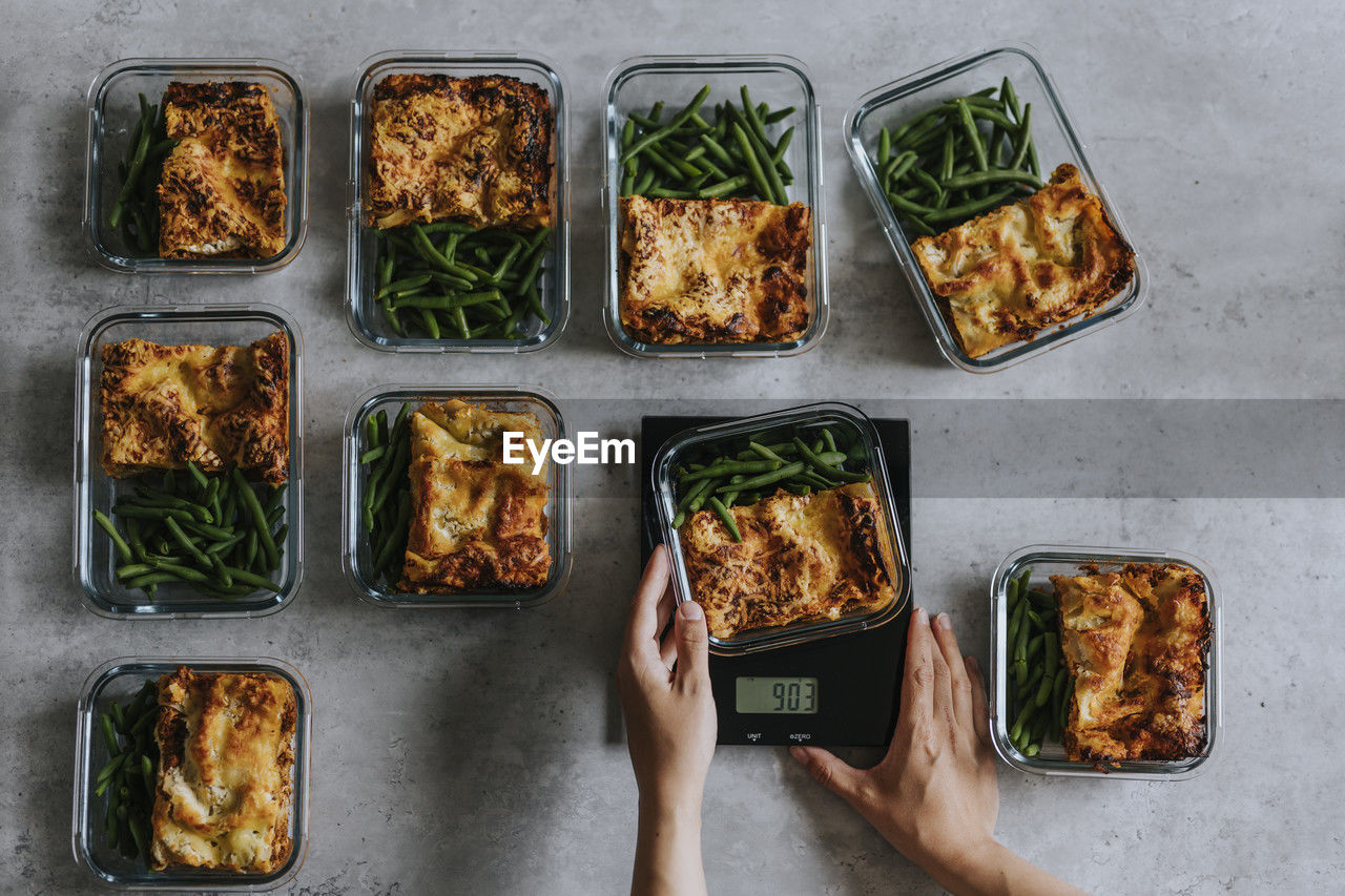 Overhead view of person weighing lunch boxes as part of healthy meal prep