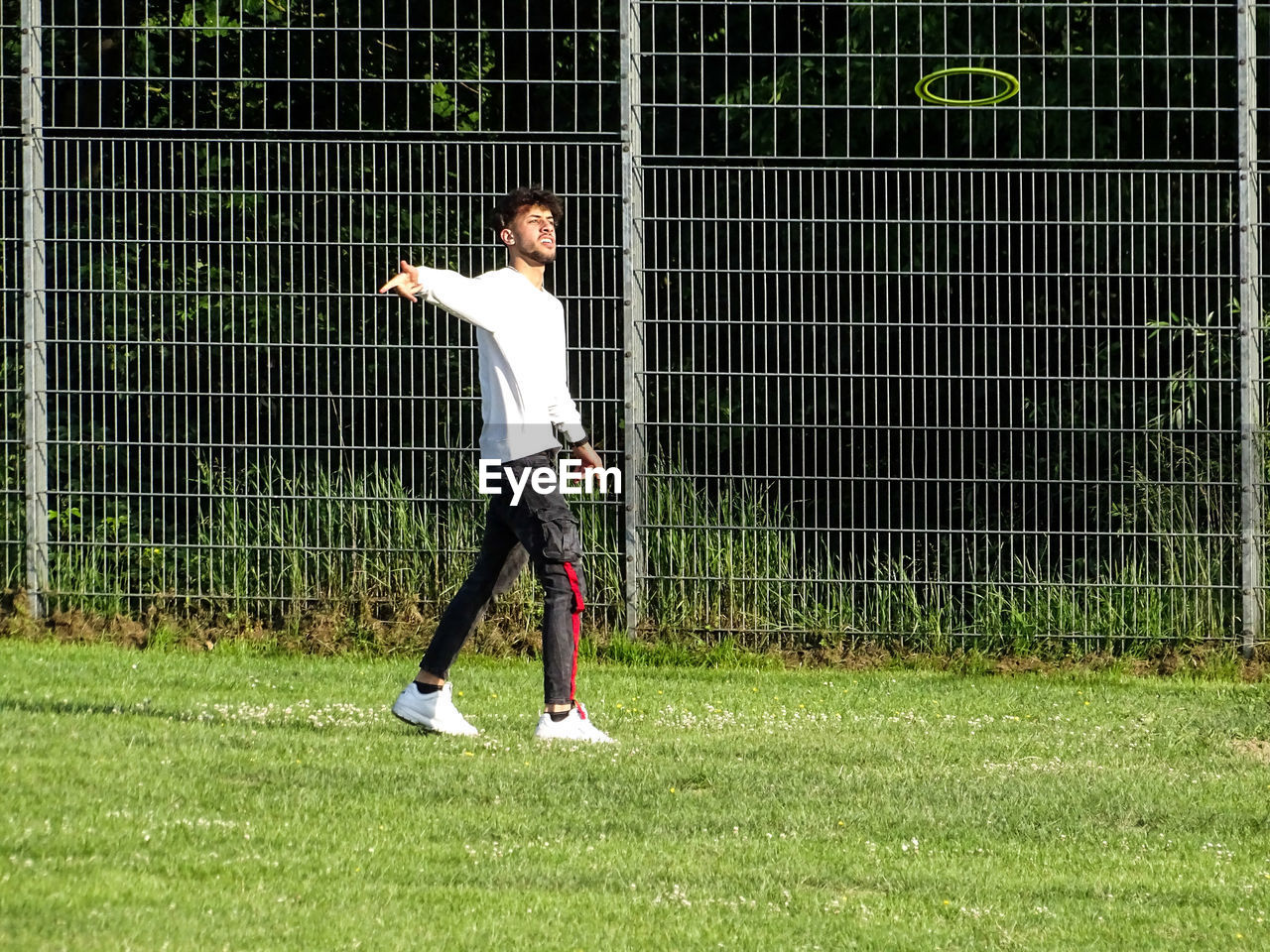 Full length of man walking while throwing plastic disc on grass