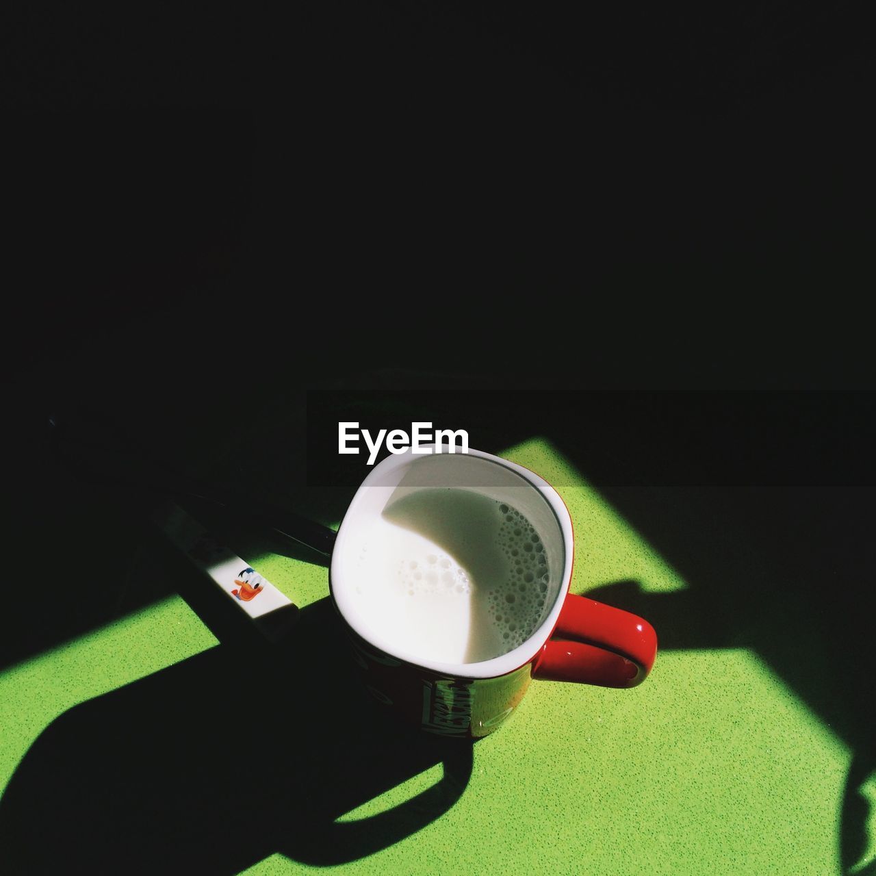 Close-up overhead view of coffee cup on green surface