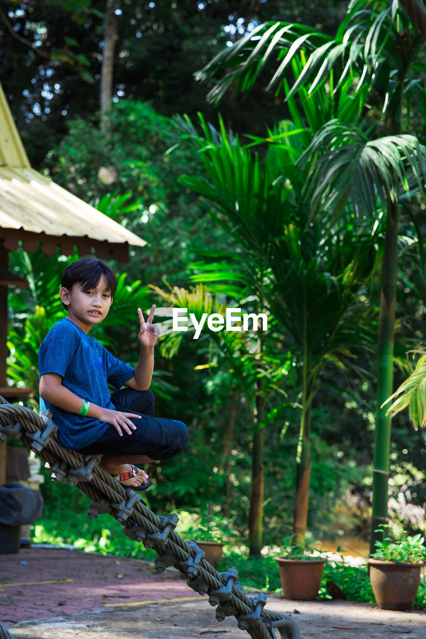 Portrait of boy gesturing while standing in park