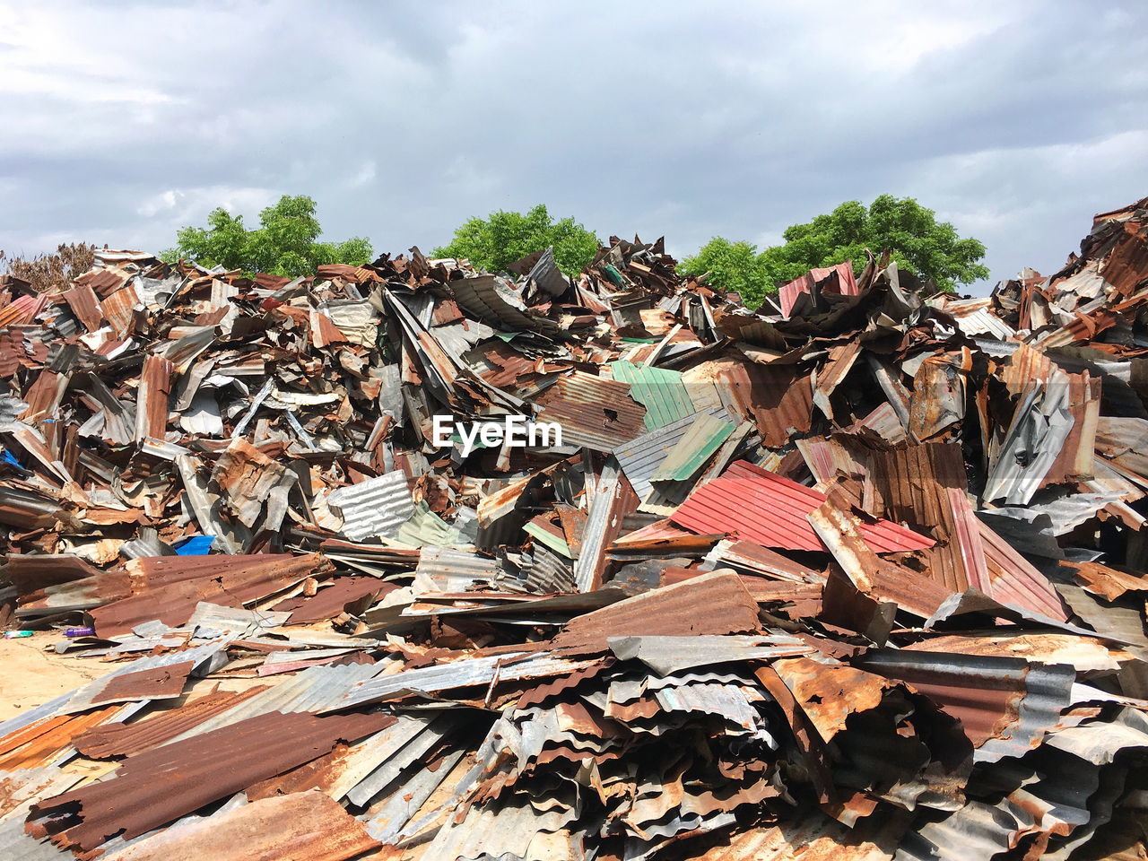 Heap of scrap metals against cloudy sky at garbage dump