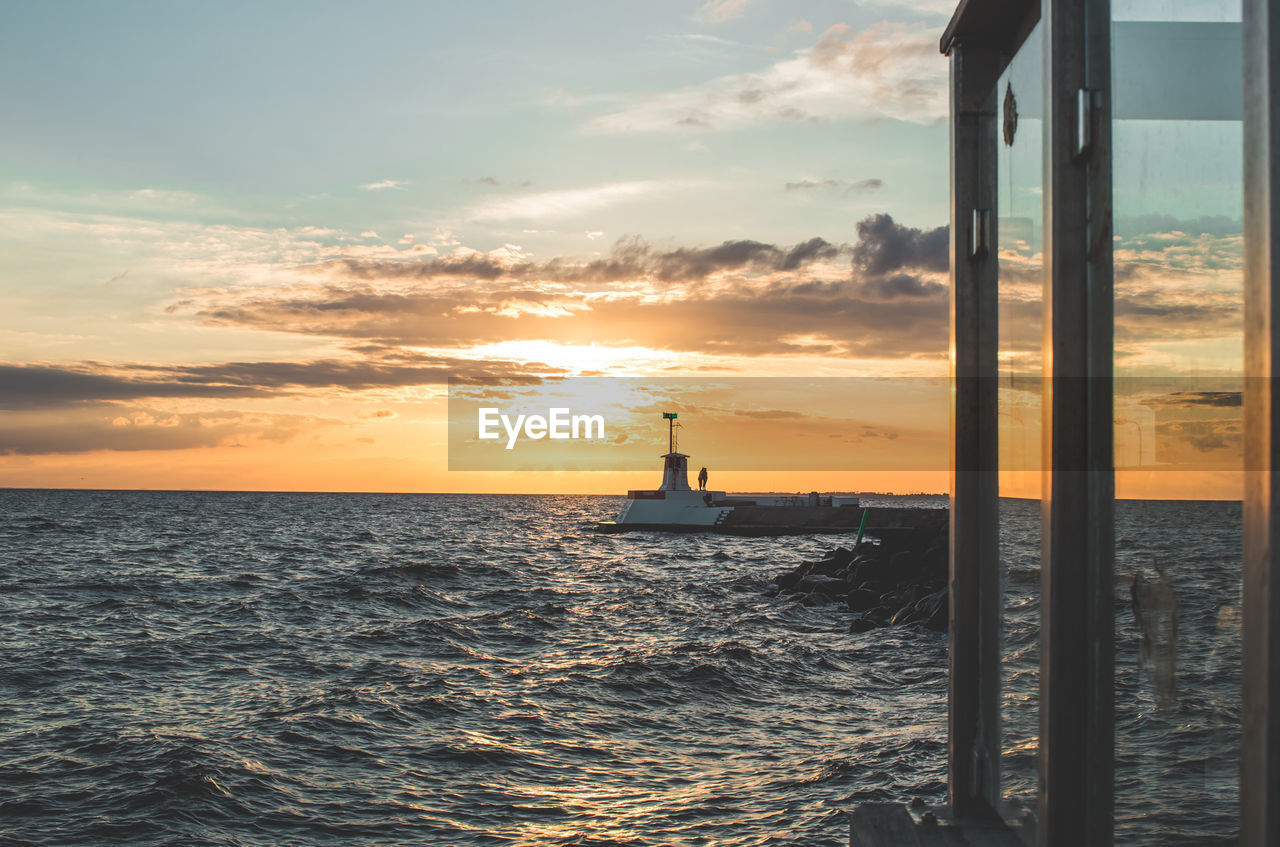 Boat sailing in sea against sky during sunset