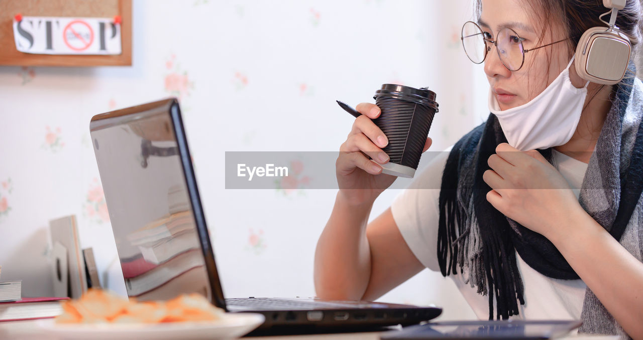 MIDSECTION OF WOMAN WORKING ON TABLE AT HOME
