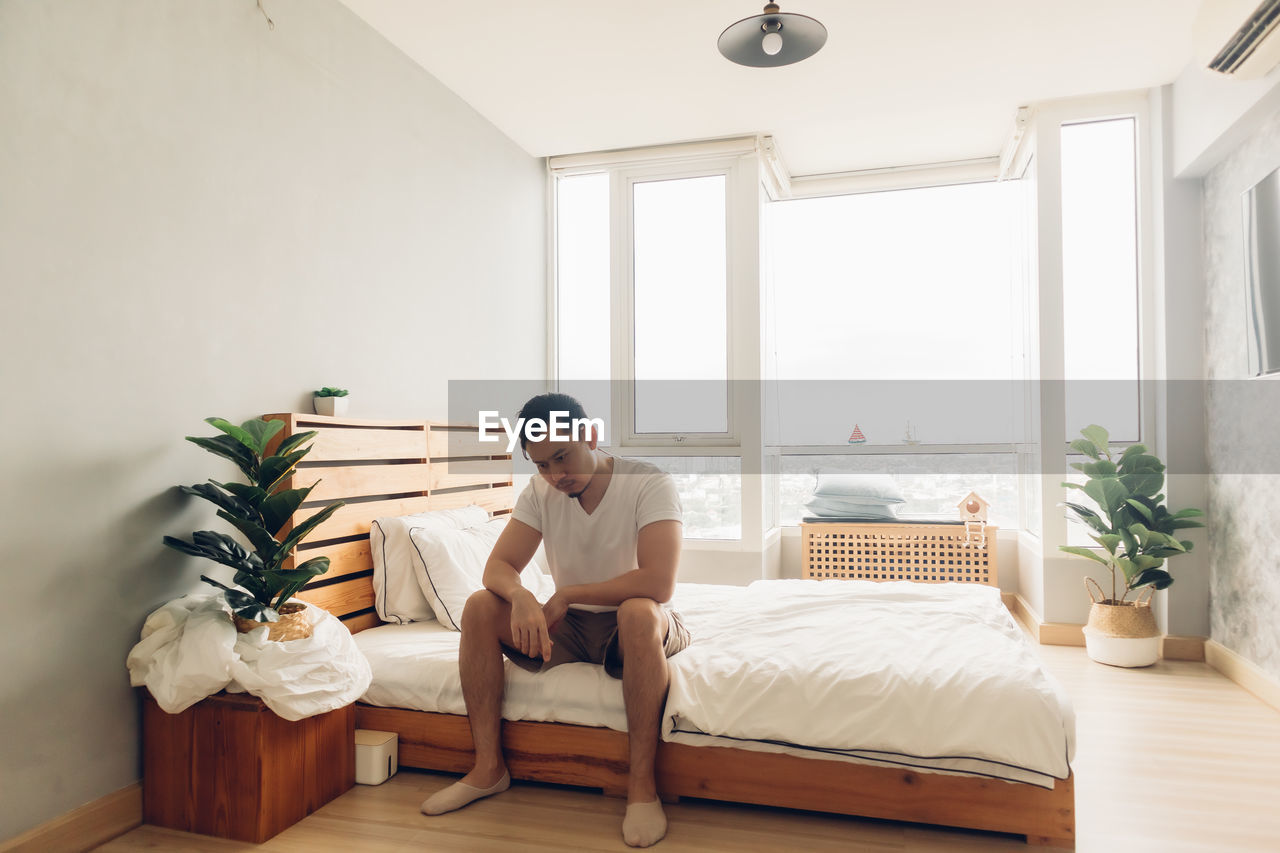 Lonely and depressed man in his bedroom in the apartment.