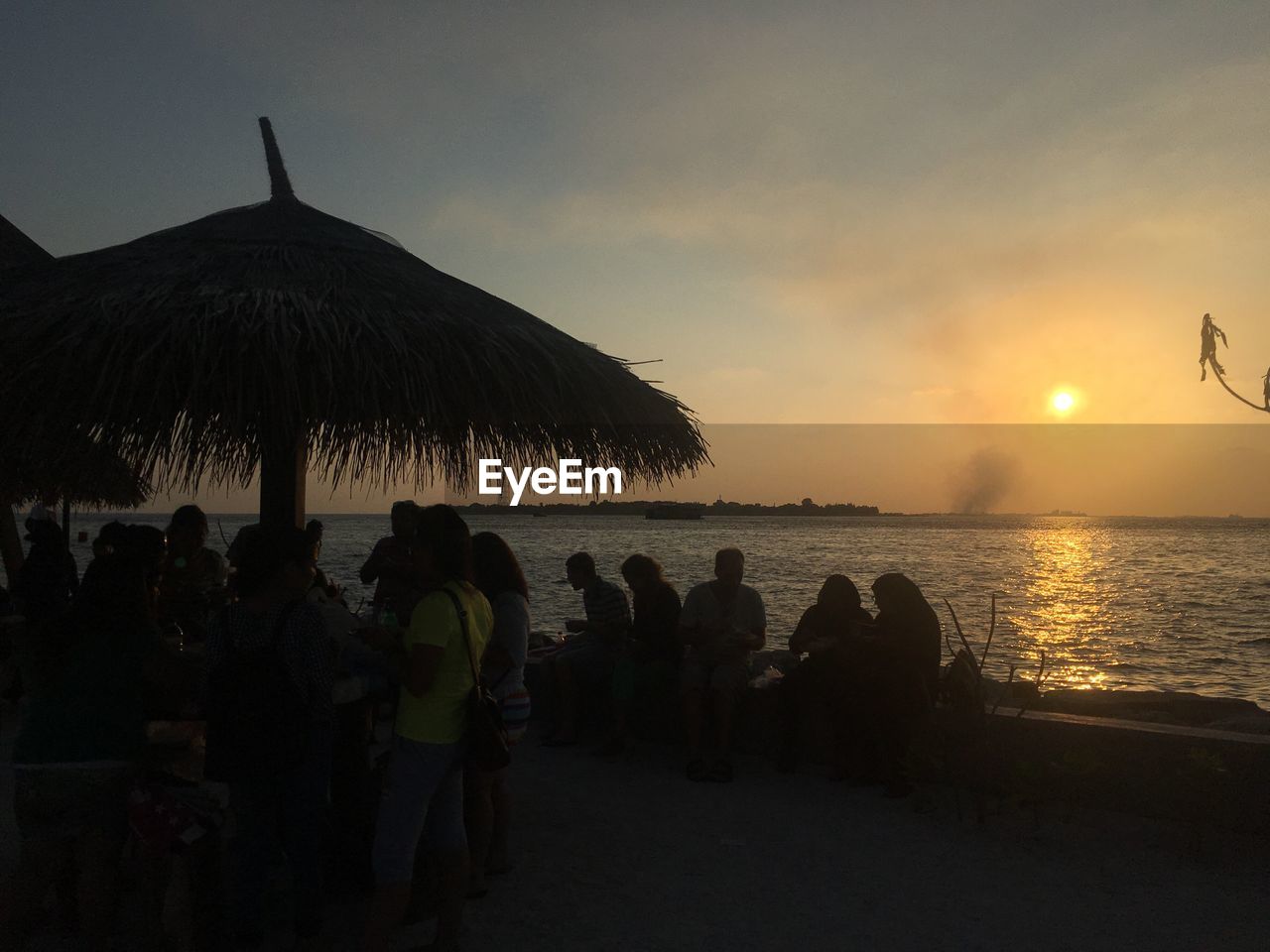 REAR VIEW OF SILHOUETTE COUPLE ON BEACH DURING SUNSET