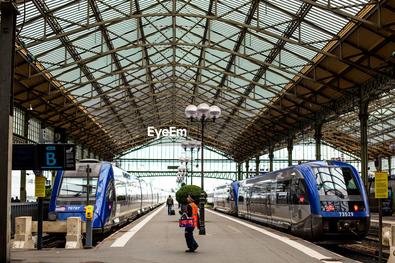 REAR VIEW OF PEOPLE STANDING ON RAILROAD STATION PLATFORM