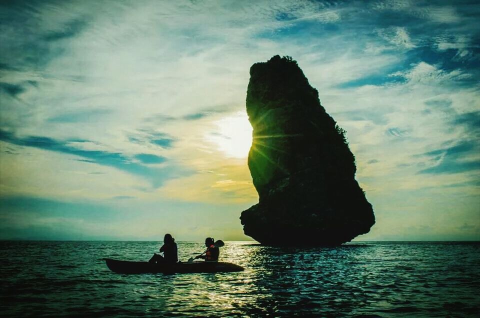 Silhouette people in boat at sunset