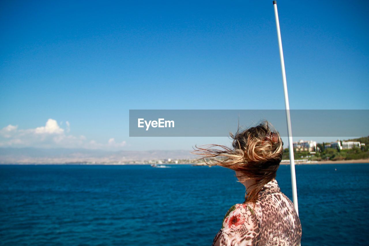 Rear view of woman looking at sea against blue sky