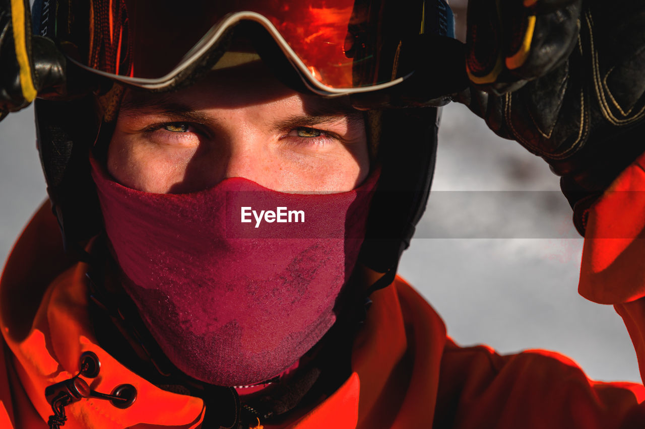 Guy in ski goggles adjusts them on his face and wearing a protective helmet, close-up. a male skier