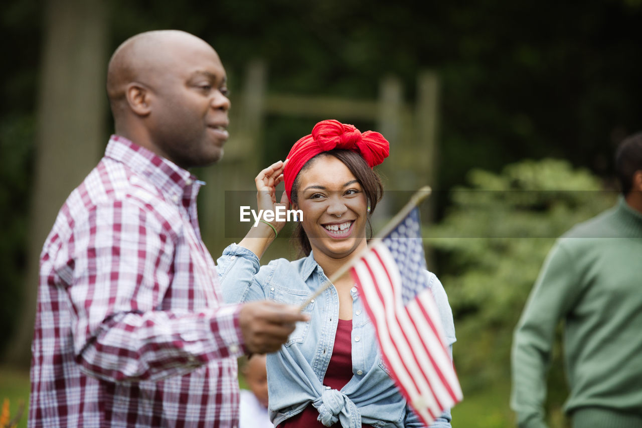 Happy woman looking at man holding american flag in backyard
