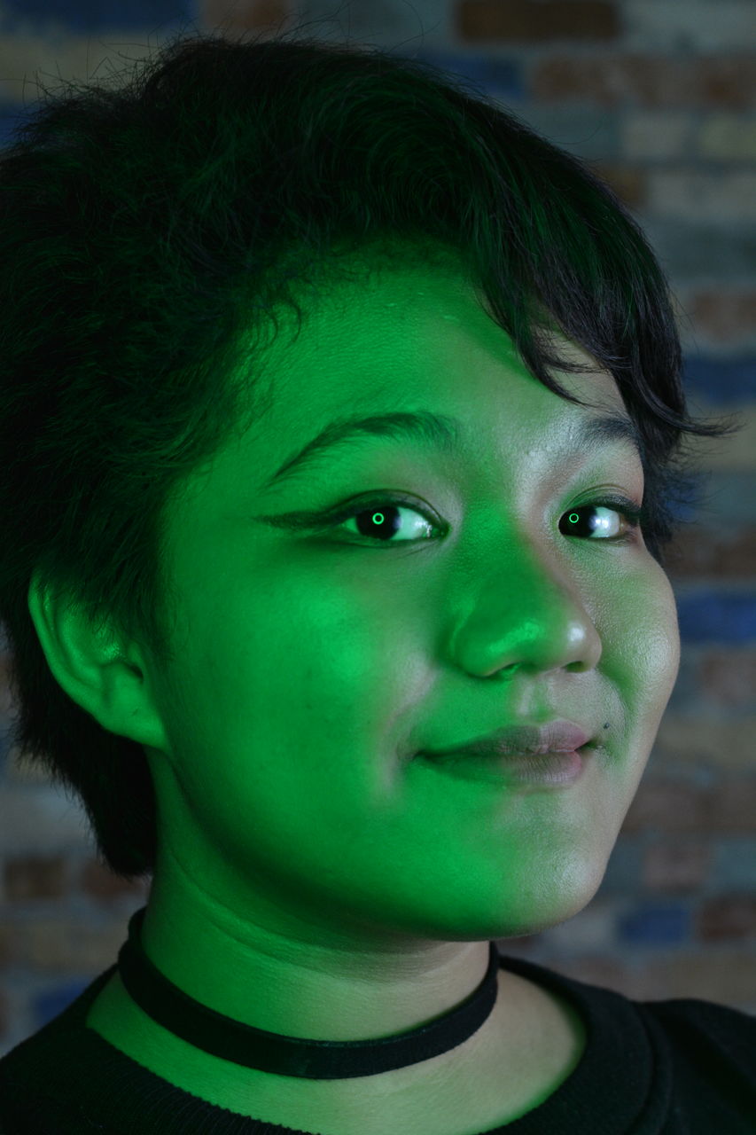 Low lit portrait of a young girl with colored light as accent