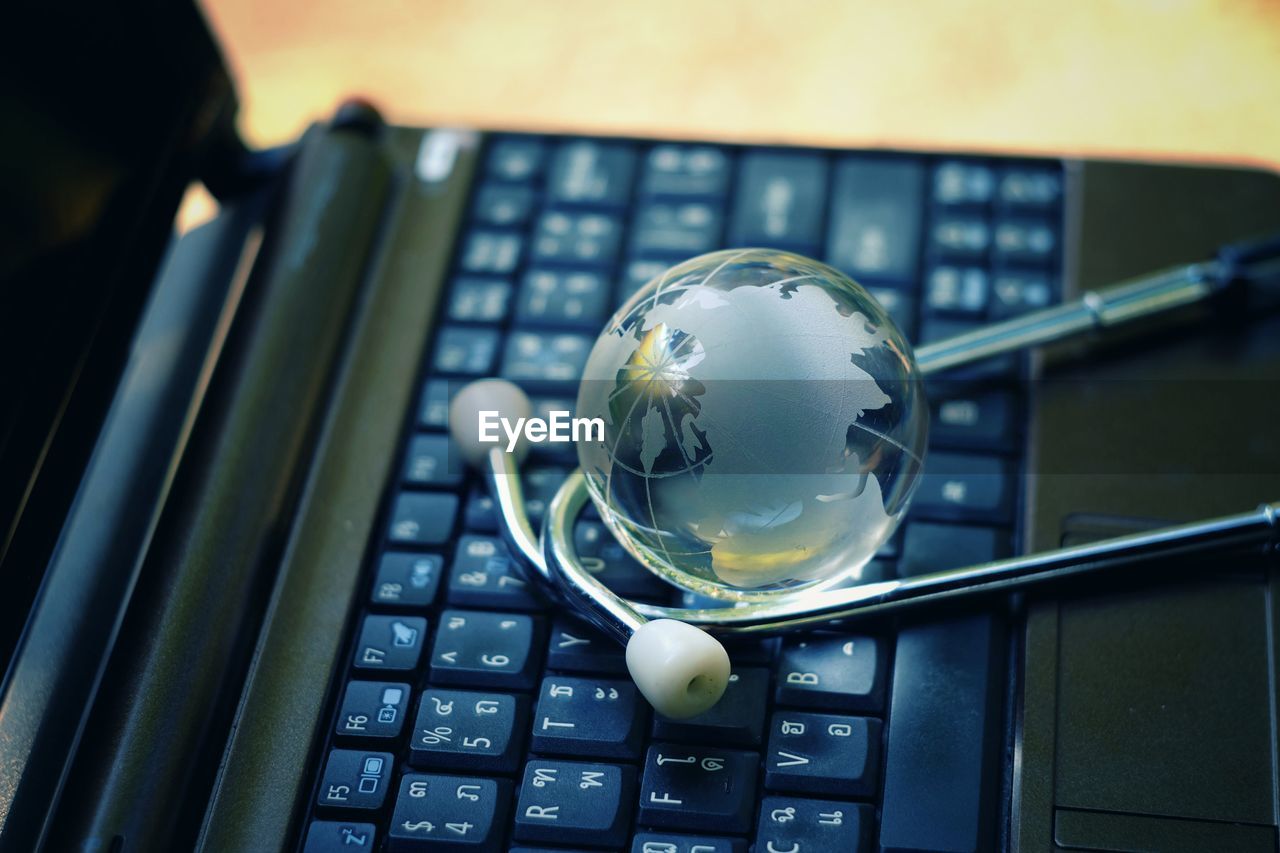 Close-up of stethoscope and globe on laptop