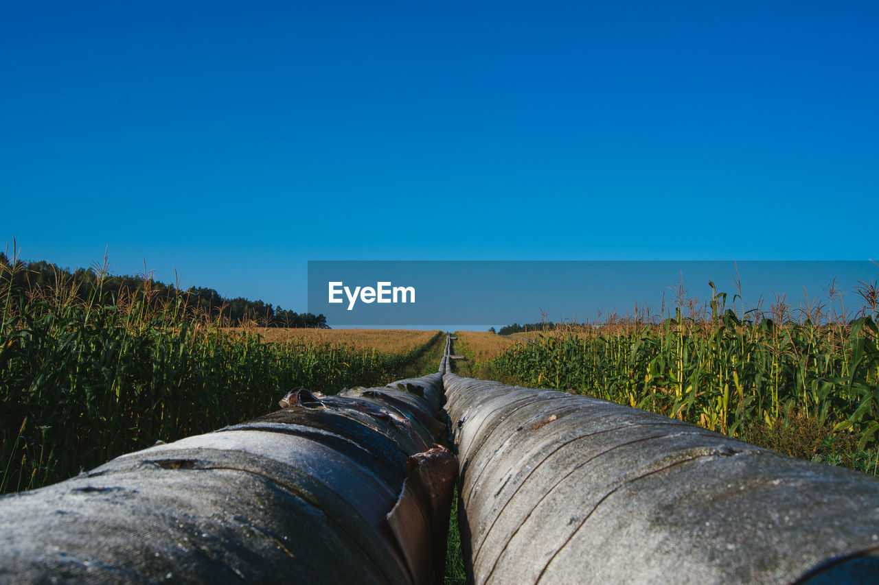 Large pipelines amidst field against clear blue sky