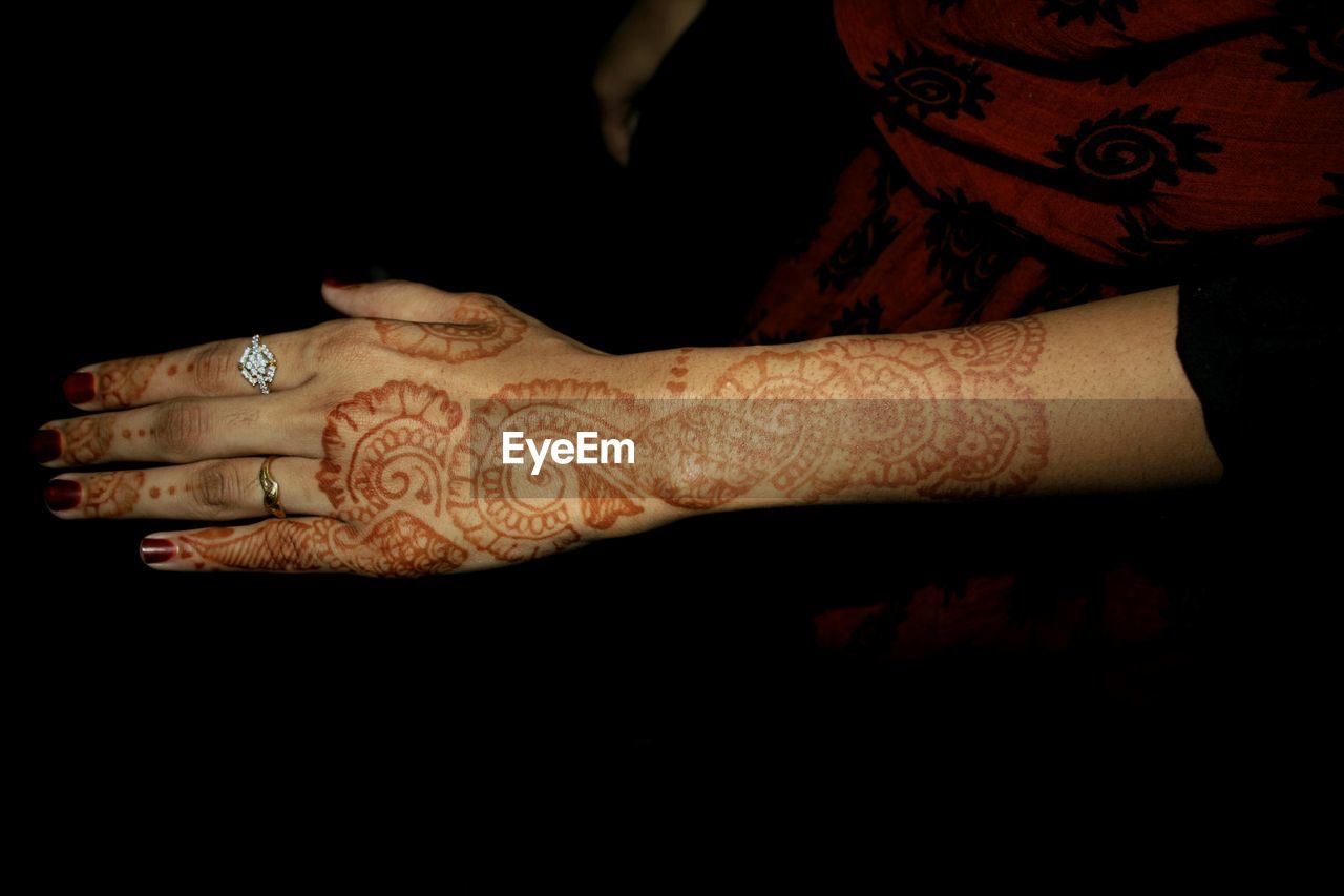 Midsection of woman with henna tattoo on hand