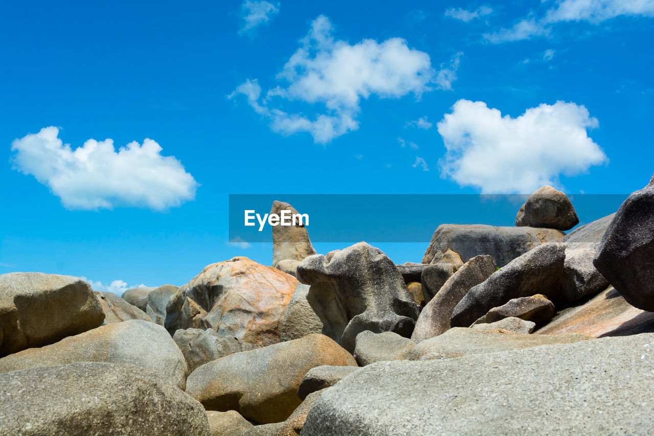 Rocks on beach against blue sky