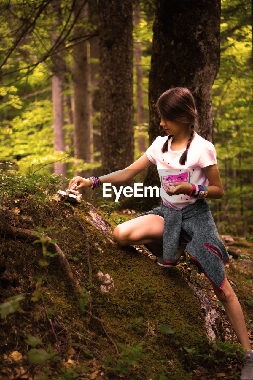 Full length of girl on tree trunk in forest