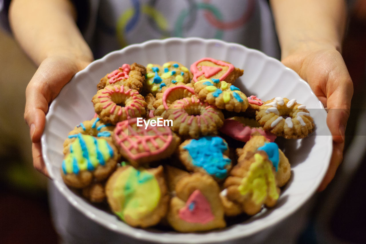 Close-up of hand holding a plate full of colorful homemade biscuits 