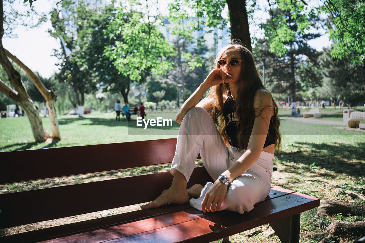 Portrait of young woman sitting on bench at park