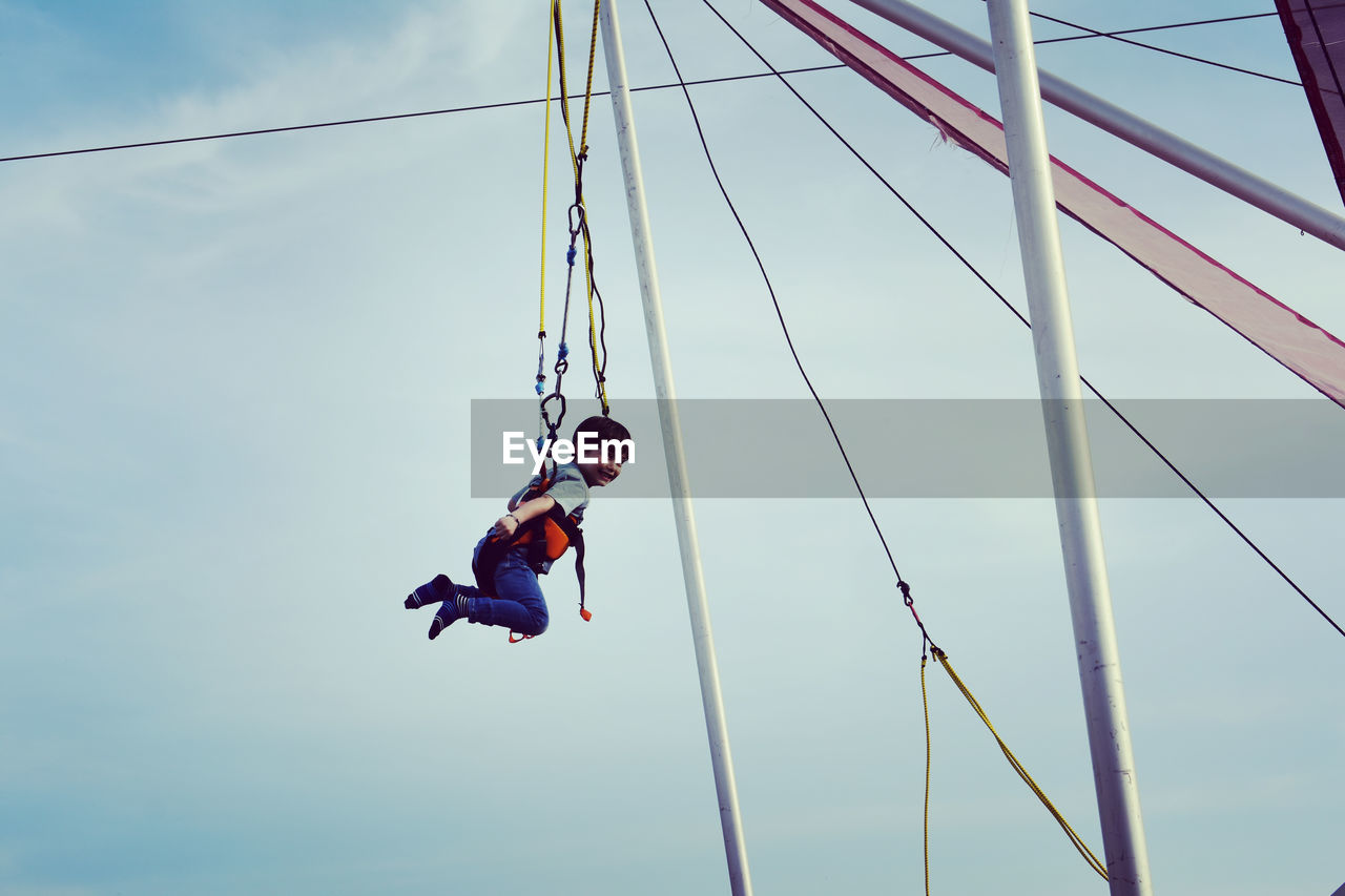 LOW ANGLE VIEW OF CHILDREN SWING AT PLAYGROUND