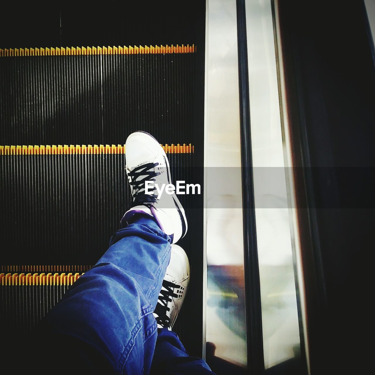 Low section of man standing on escalator