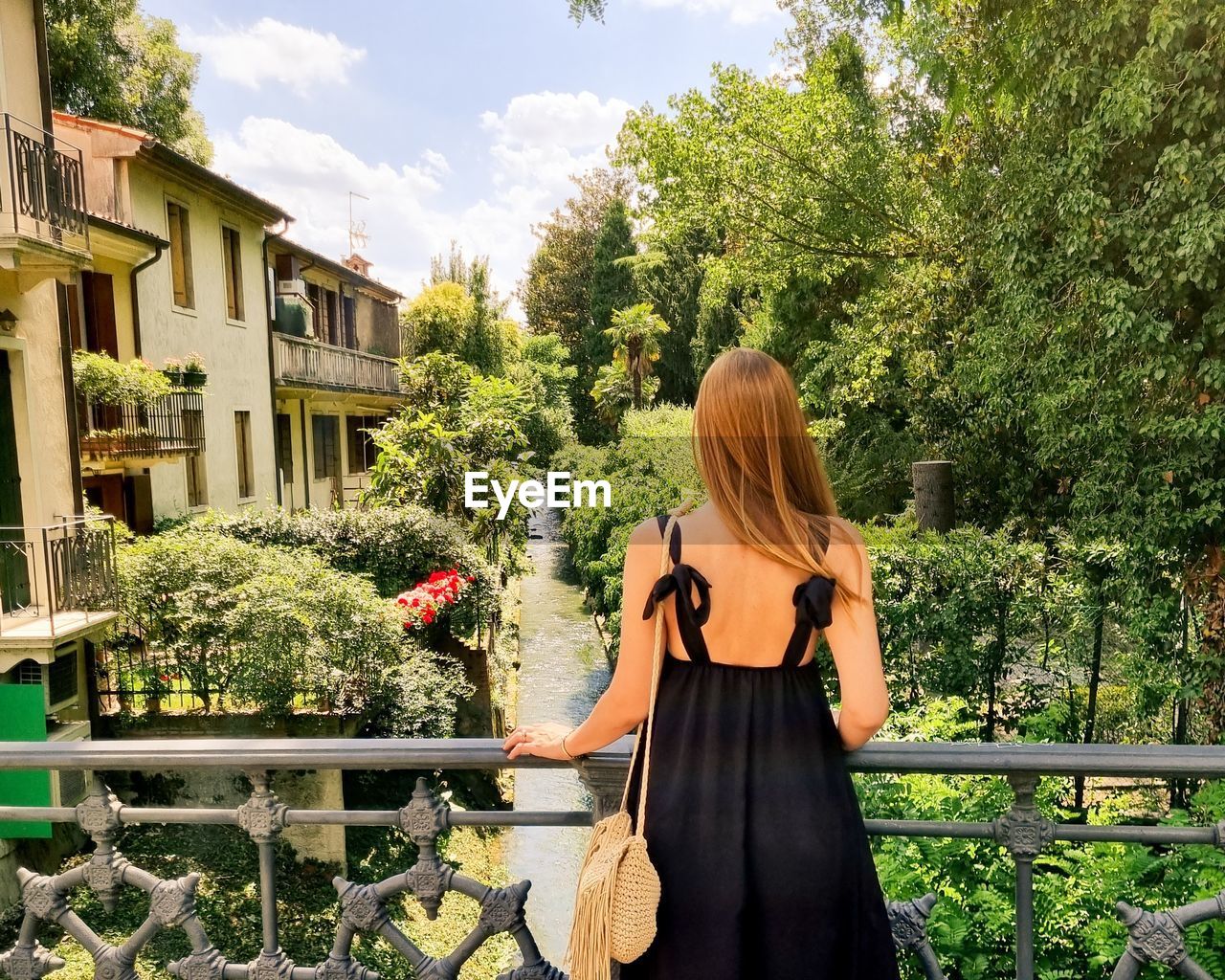 Woman standing by plants against trees