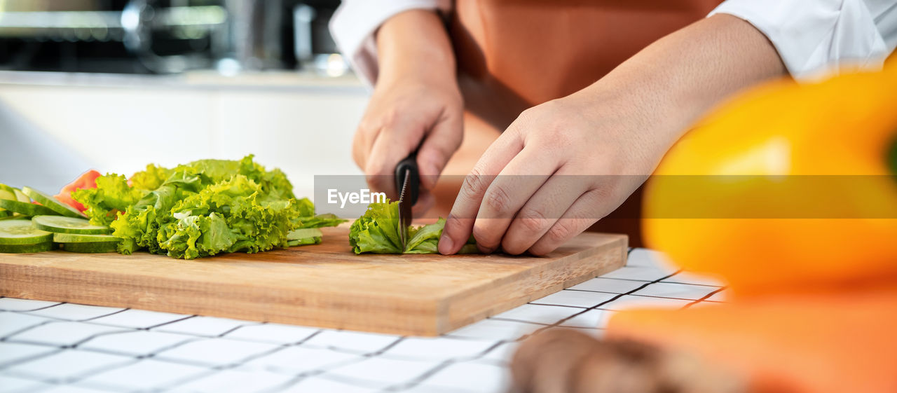 MIDSECTION OF WOMAN PREPARING FOOD AT HOME