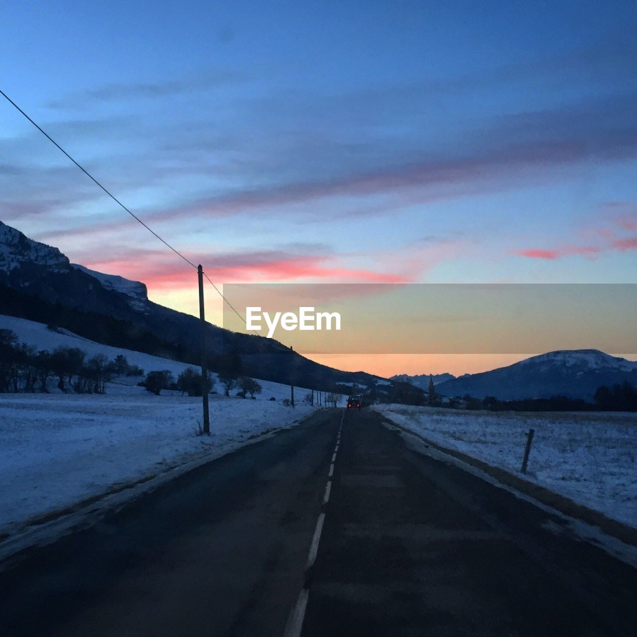 ROAD BY ELECTRICITY PYLON AGAINST SKY