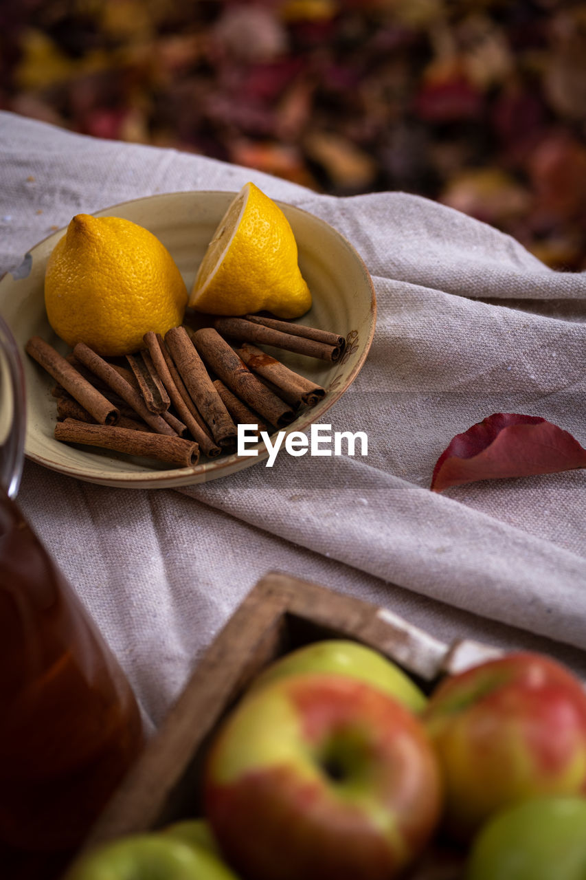 Close-up of  sliced lemon, apples and cinnamon sticks on table