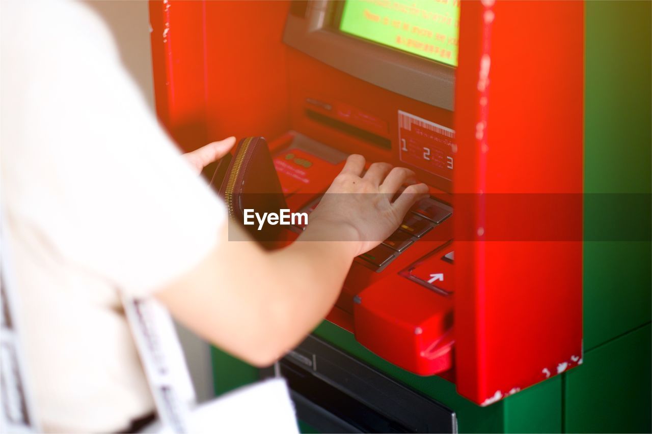 Midsection of woman using atm machinery