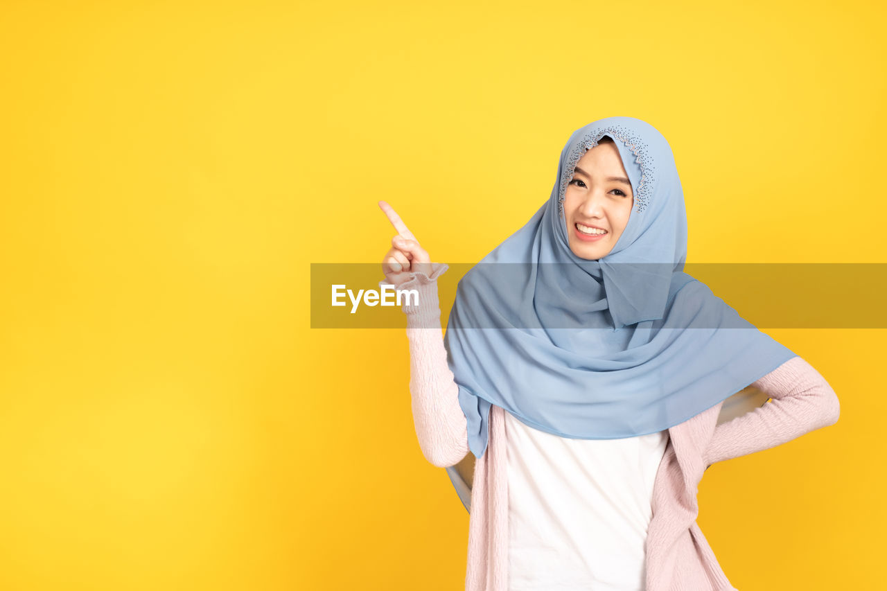 WOMAN STANDING AGAINST YELLOW WALL