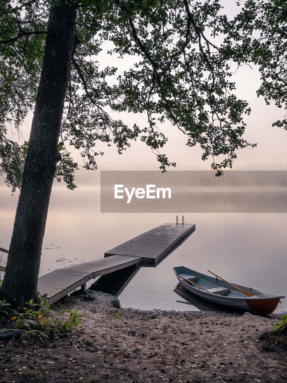 BOATS MOORED ON LAKE AGAINST SKY