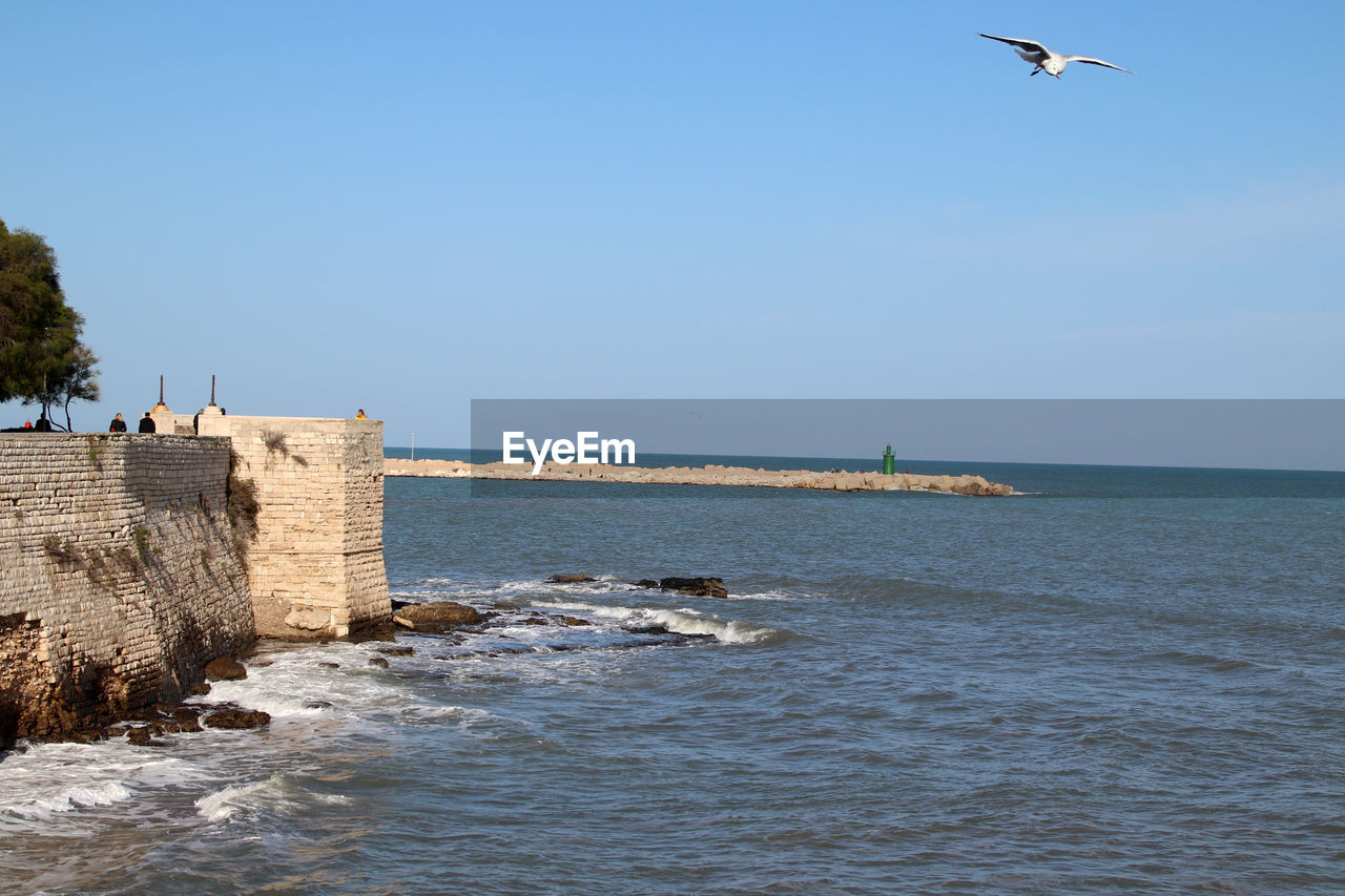 Trani, italy, 4 december 2022, public gardens, the medieval wall and the pier of san nicola