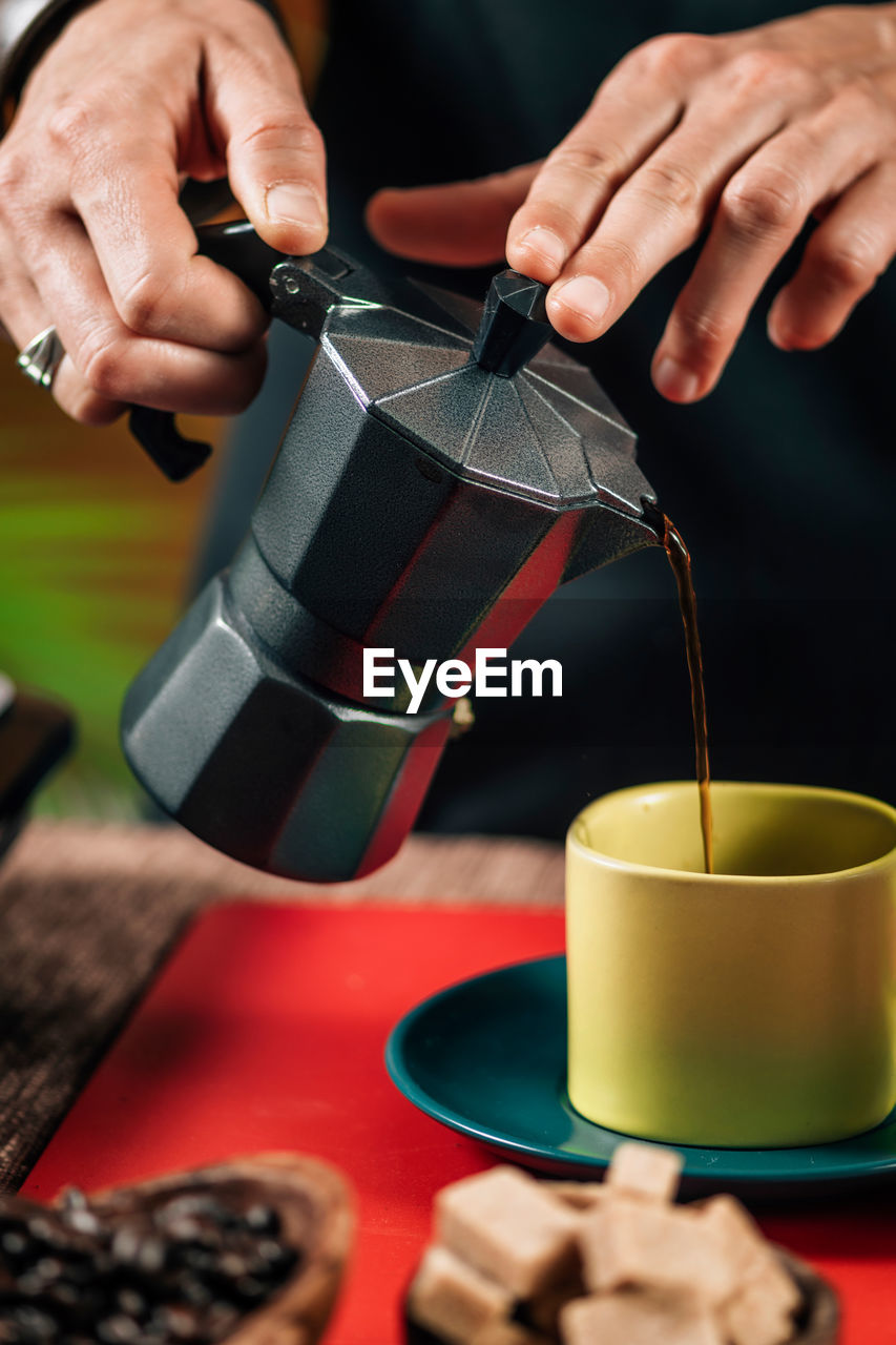 Pouring coffee from a black matte stovetop moka pot